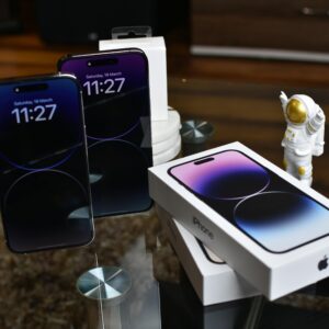 Close-up of Apple iPhone 14 Pro Max with astronaut figurine on a reflective surface.